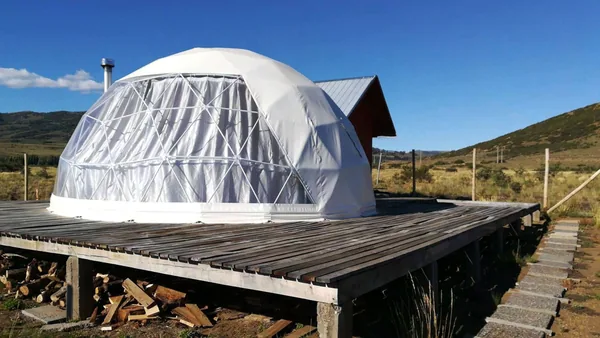 Dome op een houten vlonder met gestapeld haardhout eronder