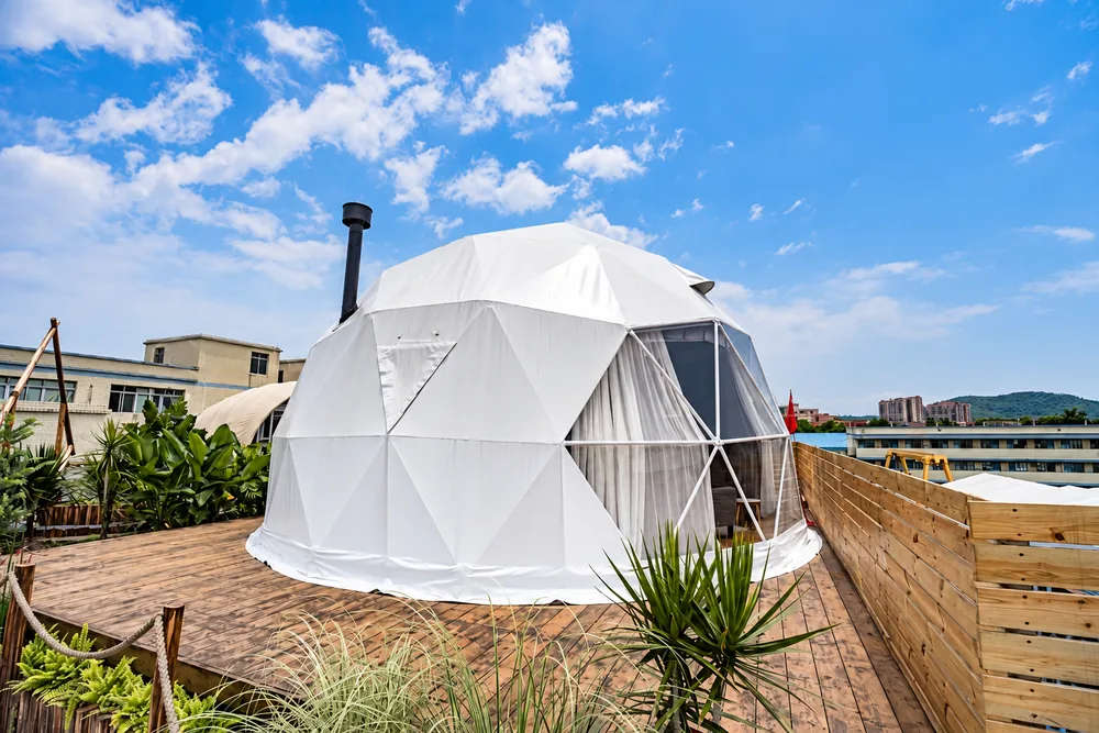 Witte dome met kacheldoorvoer op een houten vlonder onder een blauwe lucht