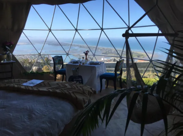 Domeinterieur met bed en gedekte tafel voor het panoramaraam