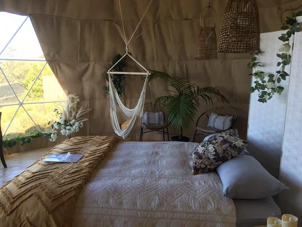 Slaapkamer in een dome met hangstoel en planten