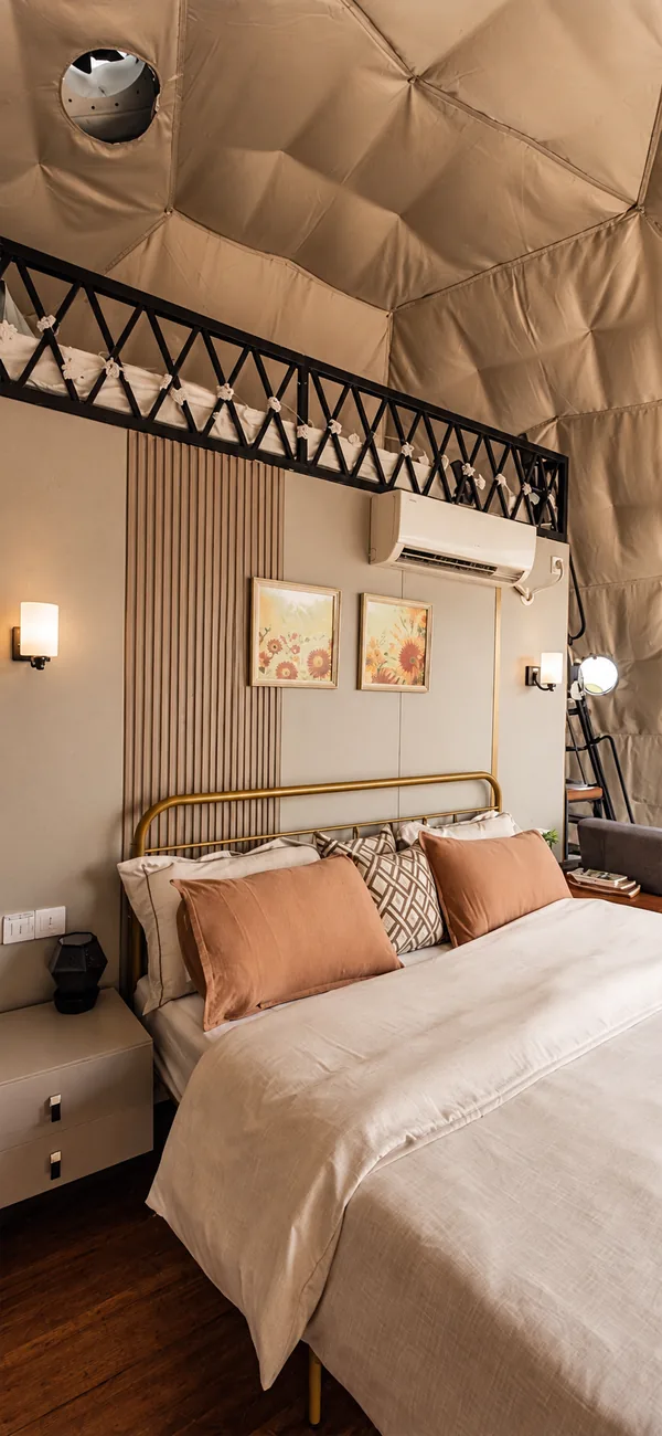 Slaapkamer in een dome met messing bedframe, wandlampen en airco-unit