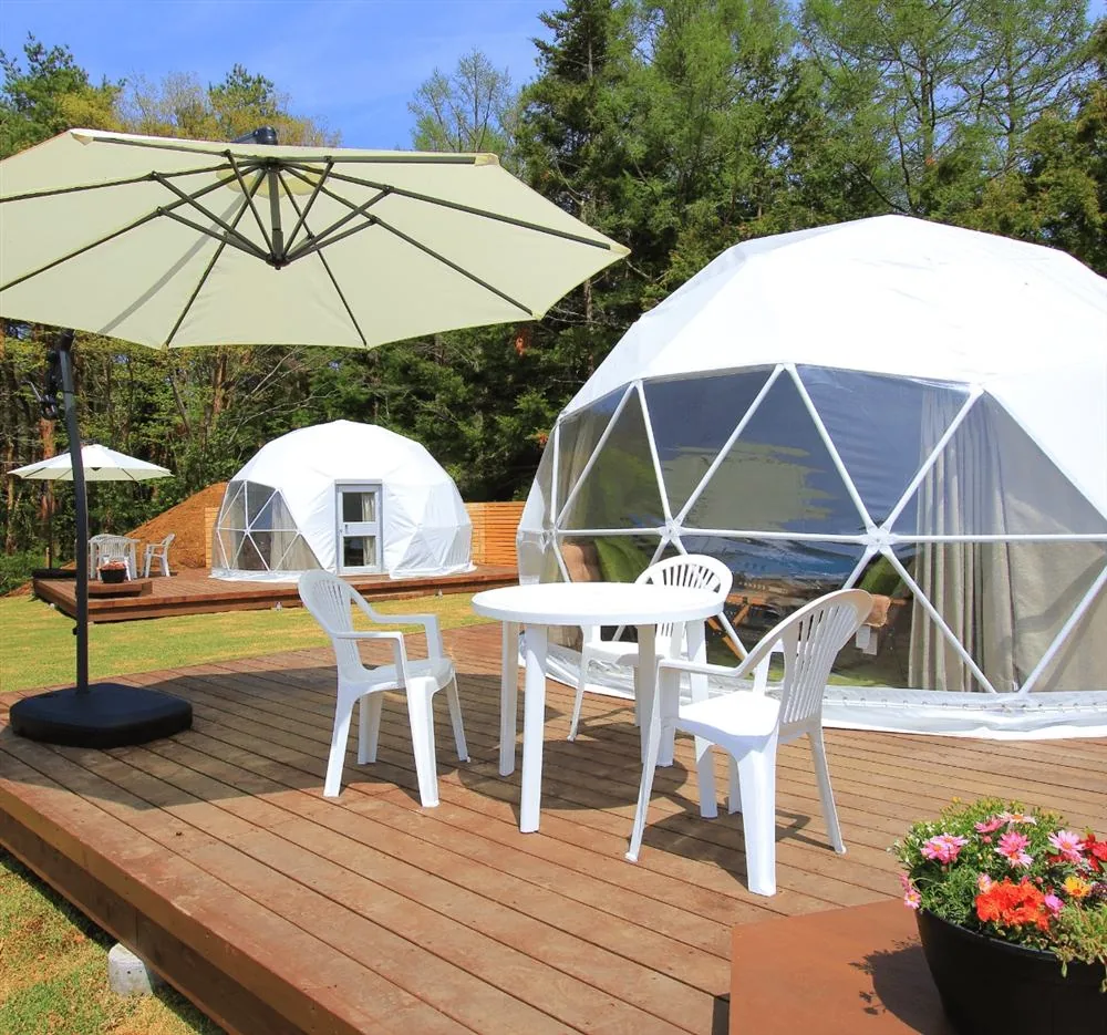 Twee domes op een grasveld met parasol en tuinmeubilair